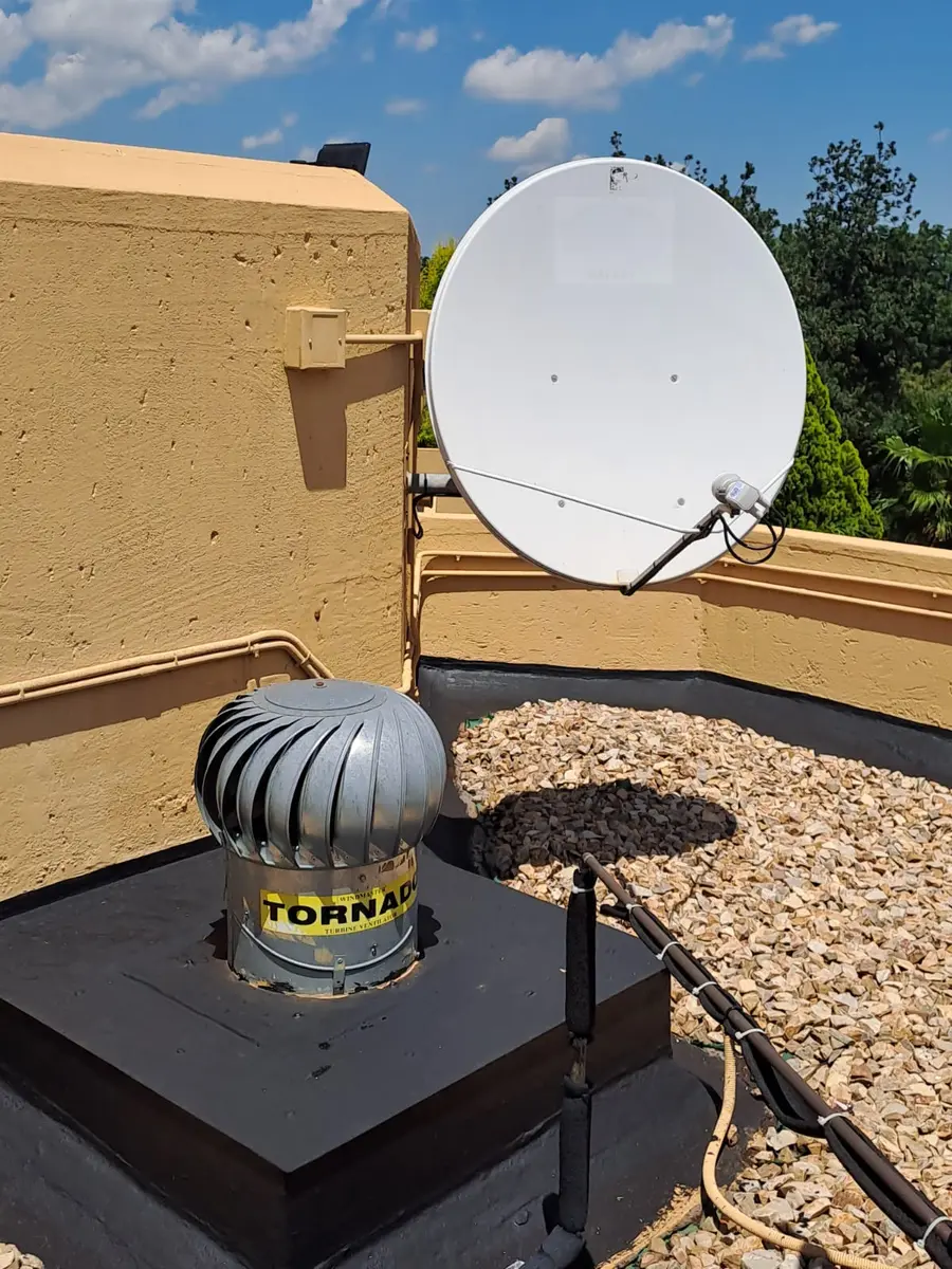 Satellite dish beside a roof parapet with routed cables